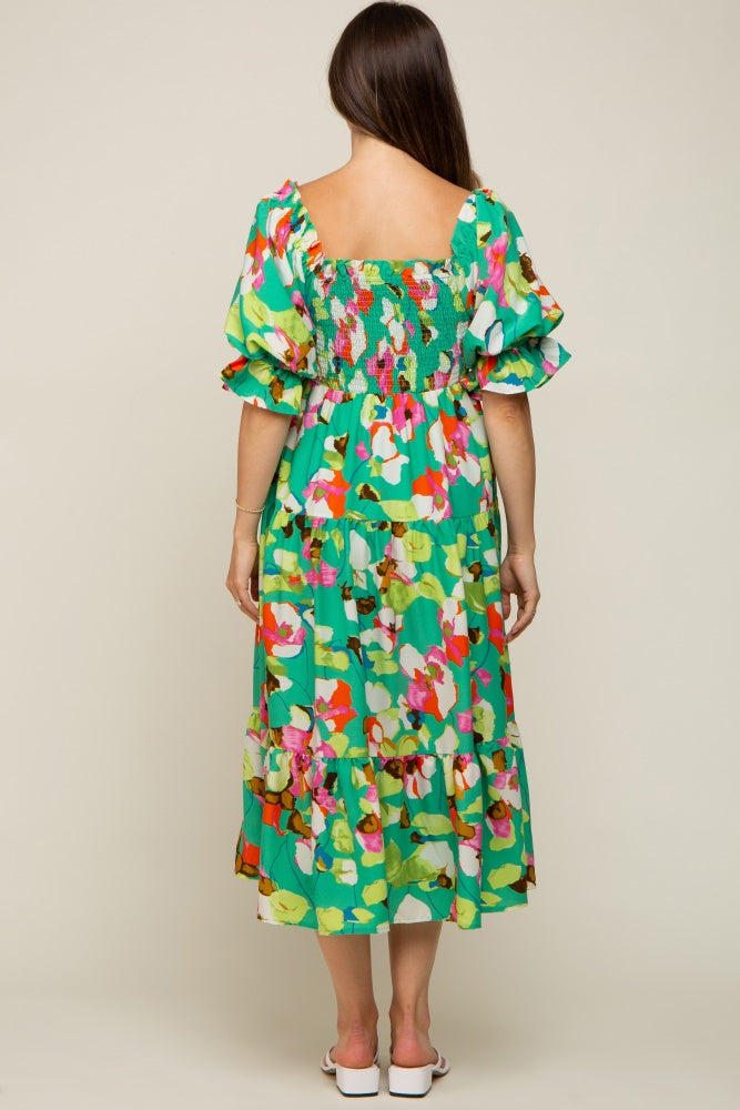 woman wearing a floral green maternity dress with puff sleeves and a tiered skirt, showing her back