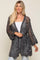 woman wearing a black and white open knit crochet cardigan over a white top and light wash jeans