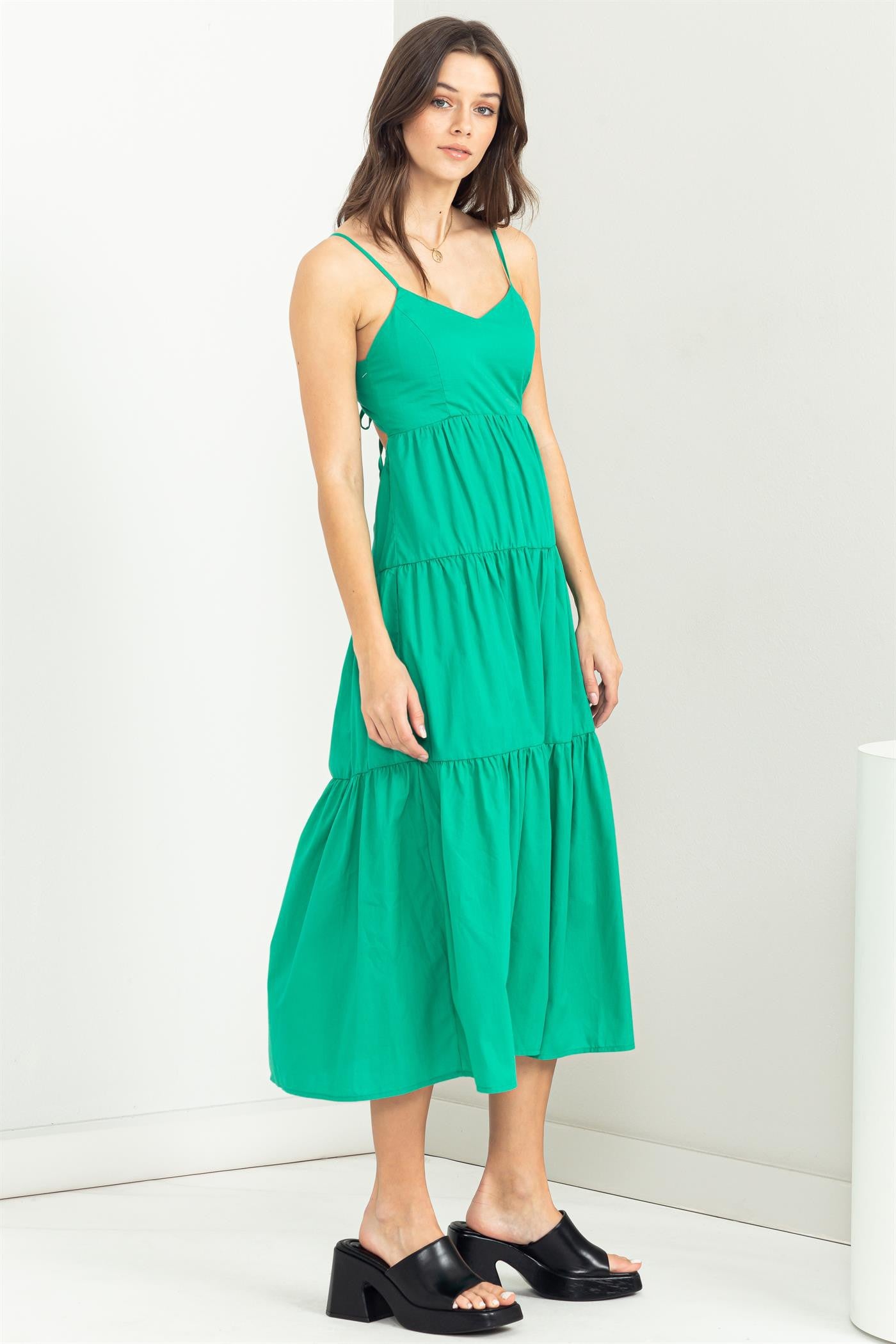 woman wearing a green tiered midi dress with spaghetti straps and black platform sandals