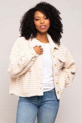 Woman with curly hair wearing a cream and tan striped sherpa jacket over a white t-shirt and blue jeans