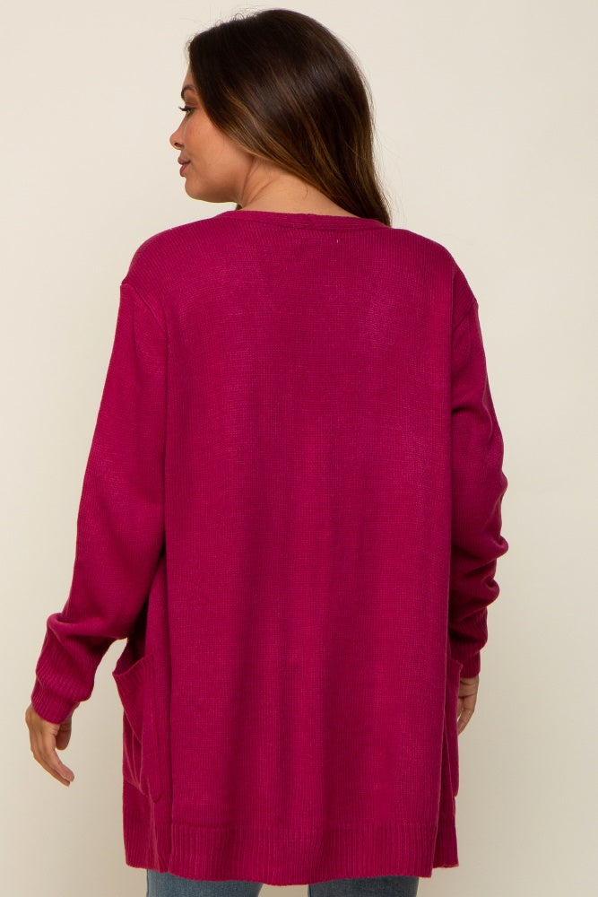Back view of a woman wearing a long magenta knit cardigan with side pockets
