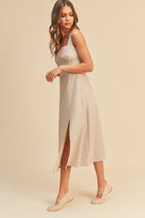 woman wearing a beige linen midi dress with a side slit and matching flat shoes