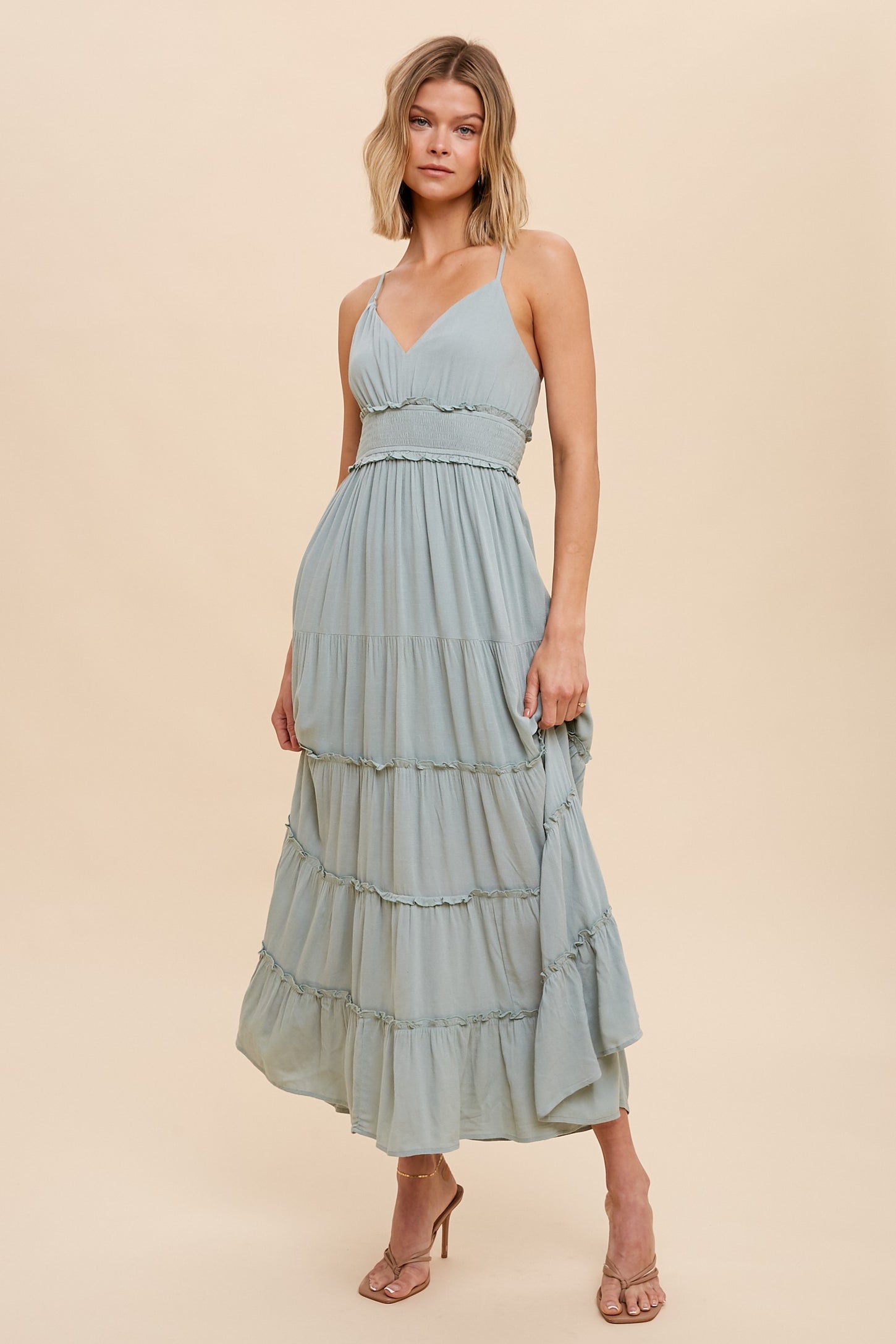 woman wearing a sage green tiered maxi dress with spaghetti straps and ruffled waist detail