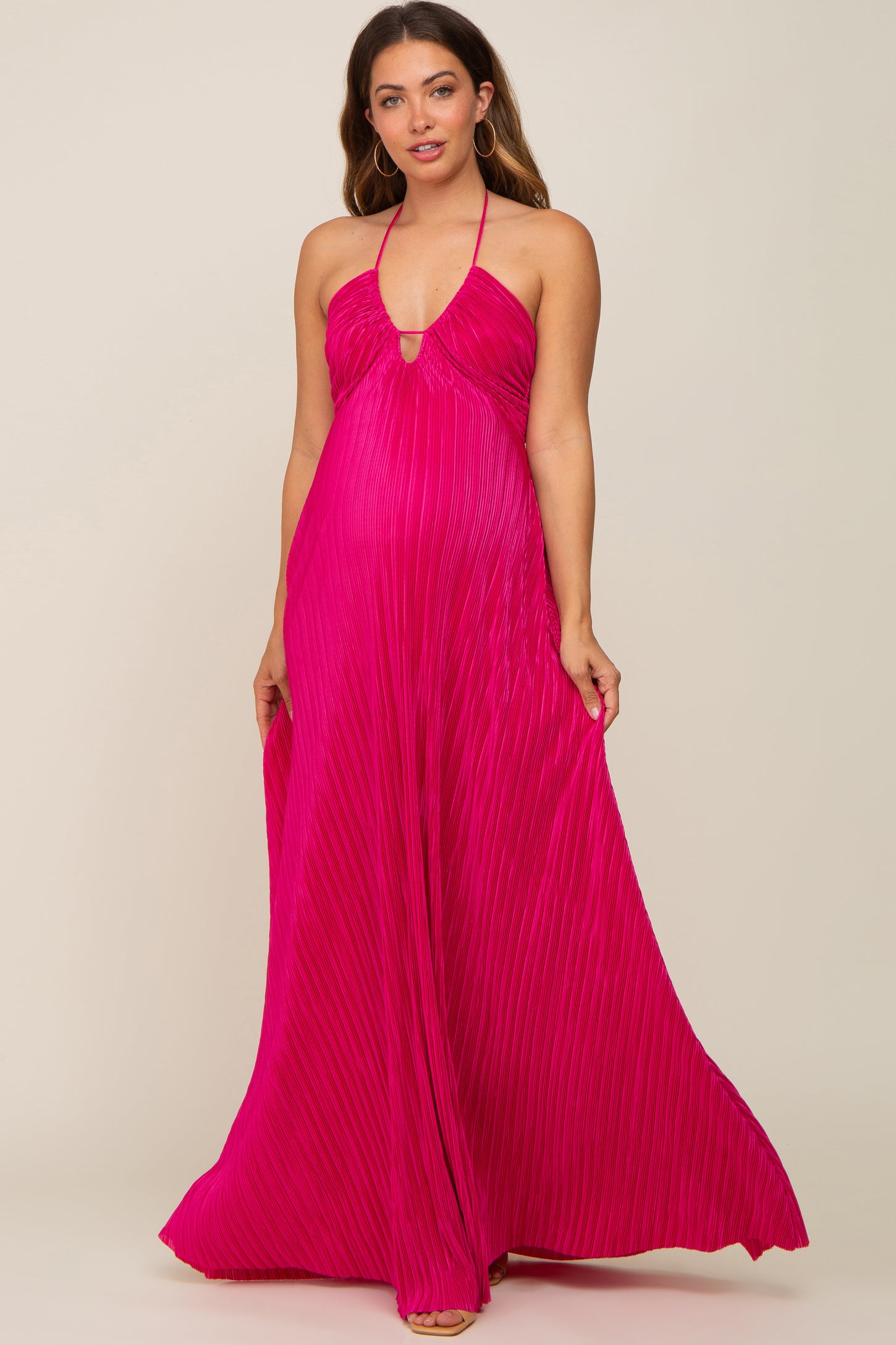 woman wearing a hot pink pleated halter neck maternity maxi dress