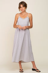 Woman wearing a striped midi sundress with spaghetti straps and embroidered neckline detail