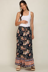 Pregnant woman in white tank top and navy floral maternity maxi skirt with ruffled hem and platform sandals