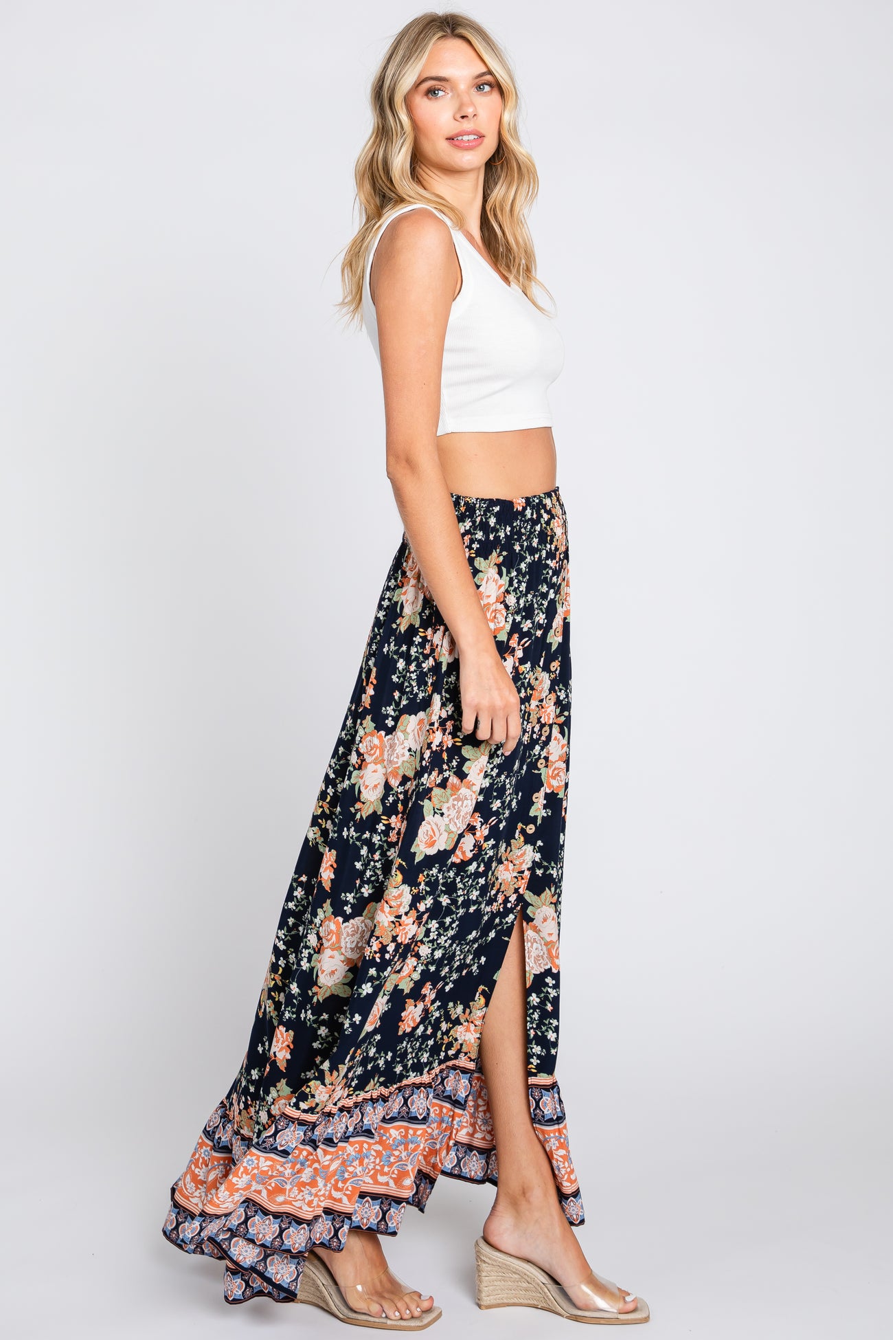 woman wearing white crop top and navy floral maxi skirt with side slit and wedge sandals