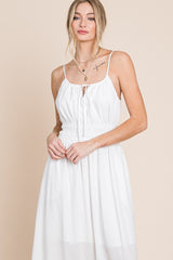 woman wearing a white sleeveless midi dress with a smocked waist and gold necklaces