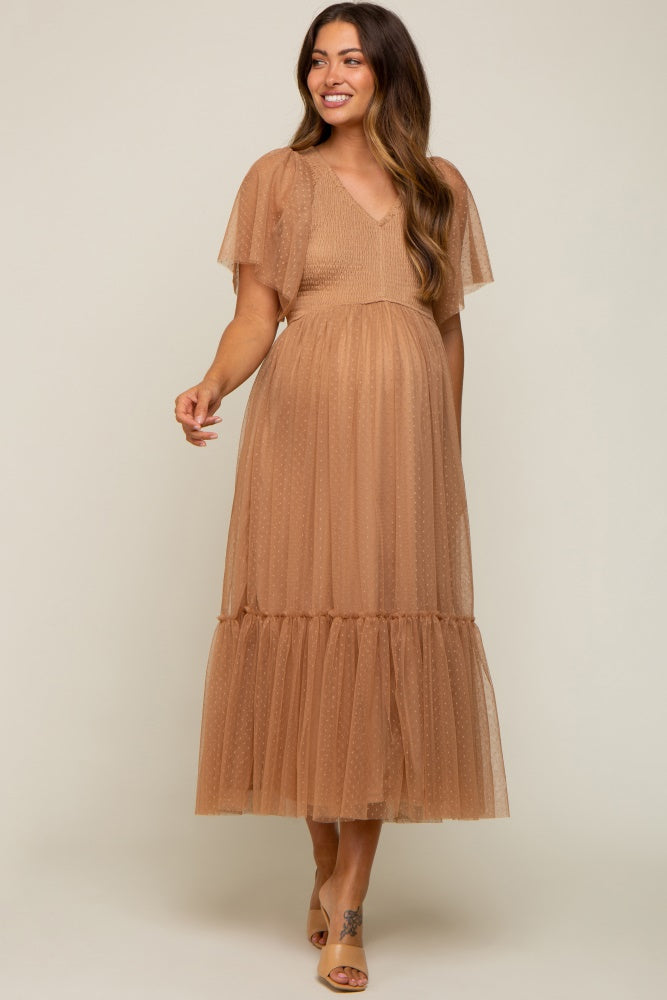 woman wearing a tan maternity dress with short flutter sleeves and a tiered tulle skirt, showcasing her baby bump