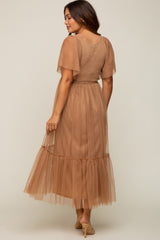 woman wearing a sheer brown maternity dress with short flutter sleeves and a tiered skirt, showing a baby bump