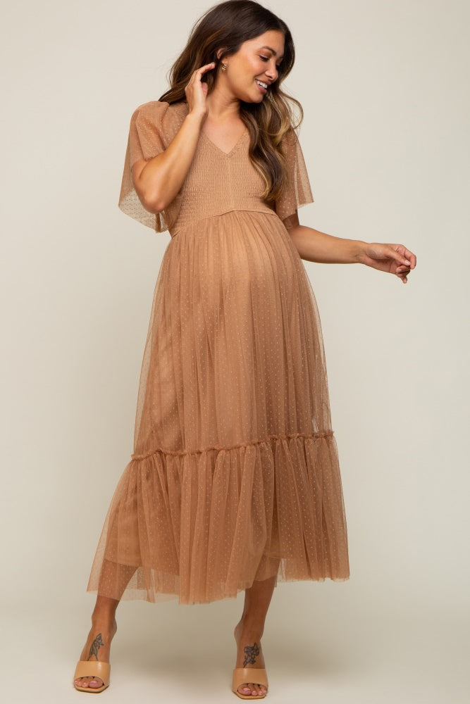 pregnant woman wearing a tan swiss dot tulle maternity midi dress with flutter sleeves