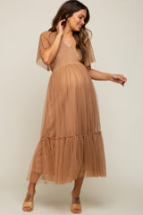 pregnant woman wearing a tan swiss dot tulle maternity midi dress with flutter sleeves