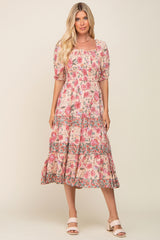 Woman wearing a pink floral smocked midi dress with puff sleeves and tiered skirt