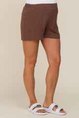 woman wearing brown linen maternity shorts with elastic waistband and white slide sandals