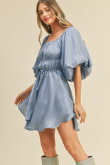 woman wearing a light blue satin mini dress with puff sleeves and a cinched waist