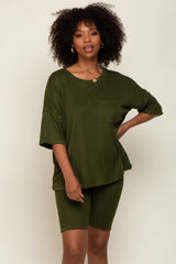 Woman wearing an olive green ribbed lounge set featuring an oversized pocket tee and matching biker shorts