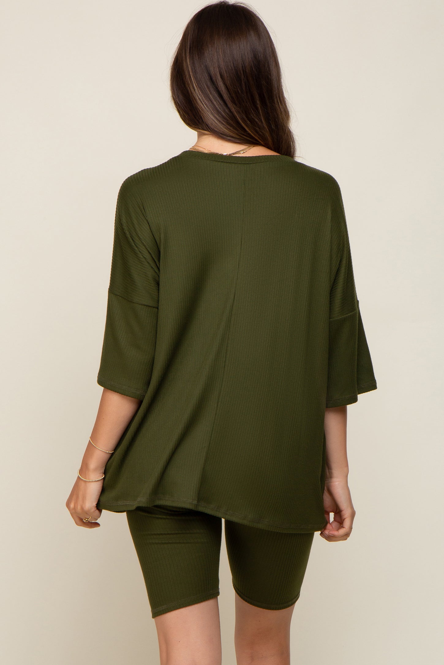 Back view of a woman wearing an olive green ribbed oversized top and matching biker shorts lounge set