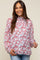 woman wearing a white mock neck maternity blouse with red and blue leaf print and long sleeves