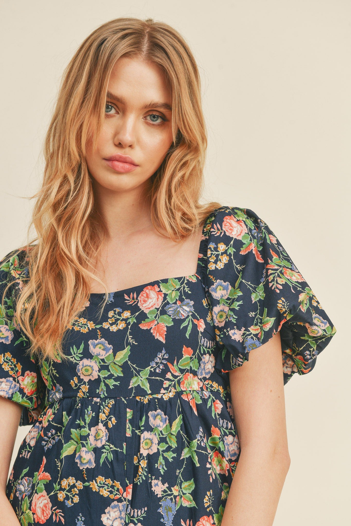 woman wearing a navy floral puff sleeve dress with a square neckline and loose fit