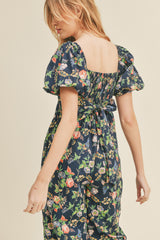 woman wearing a navy floral puff sleeve dress with a square back and tie detail