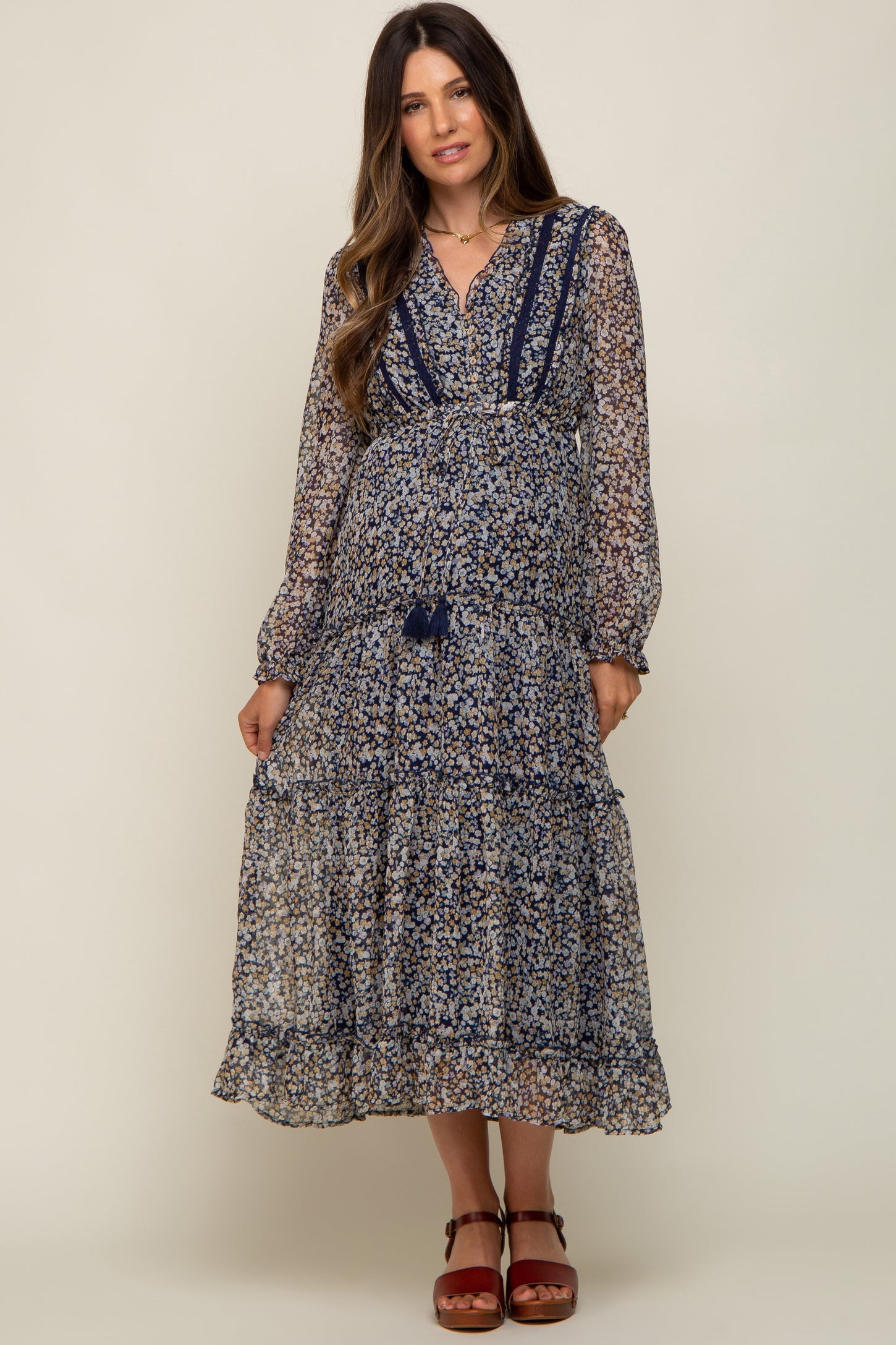 woman wearing a navy blue floral long sleeve maternity midi dress with tiered skirt and tassel tie