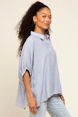 woman wearing a blue and white striped oversized button-down shirt and light wash jeans