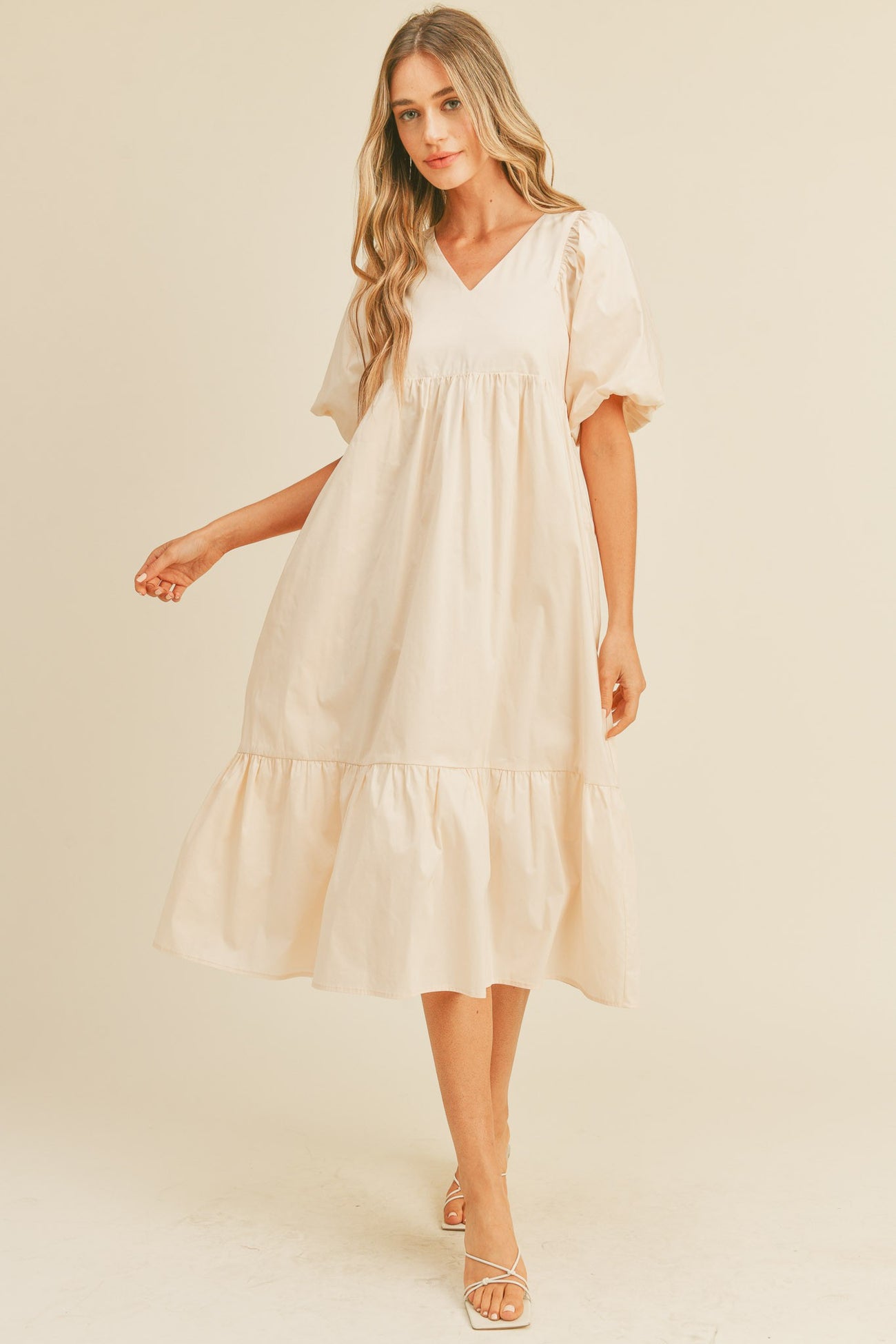 woman wearing a cream puff sleeve midi babydoll dress with a v-neckline and ruffled hem