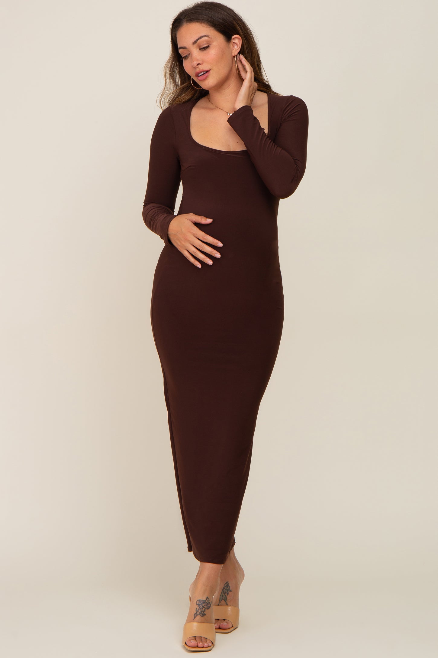 woman wearing a long sleeve brown maternity maxi dress with a scoop neckline