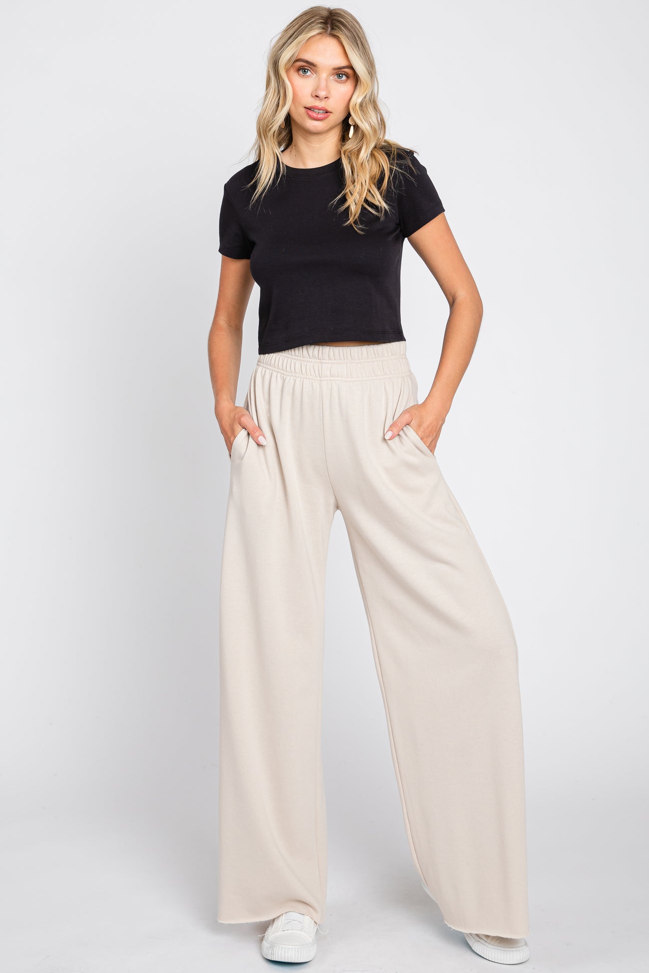 woman wearing black crop top and beige wide leg sweatpants with hands in pockets