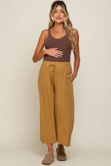 Pregnant woman wearing a brown ribbed tank top and mustard yellow wide-leg maternity pants with a drawstring waist