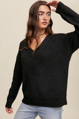 woman wearing a black v-neck ribbed knit sweater and light wash jeans against a neutral background