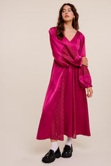 woman wearing a bright pink satin midi dress with long puff sleeves and lace details