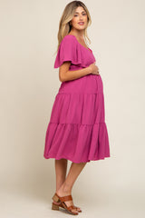pregnant woman in a magenta tiered maternity dress with flutter sleeves and brown sandals