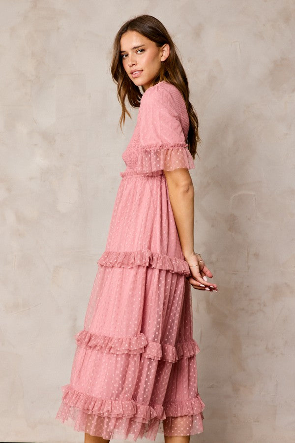 woman wearing a dusty pink midi dress with tiered ruffles and short sleeves