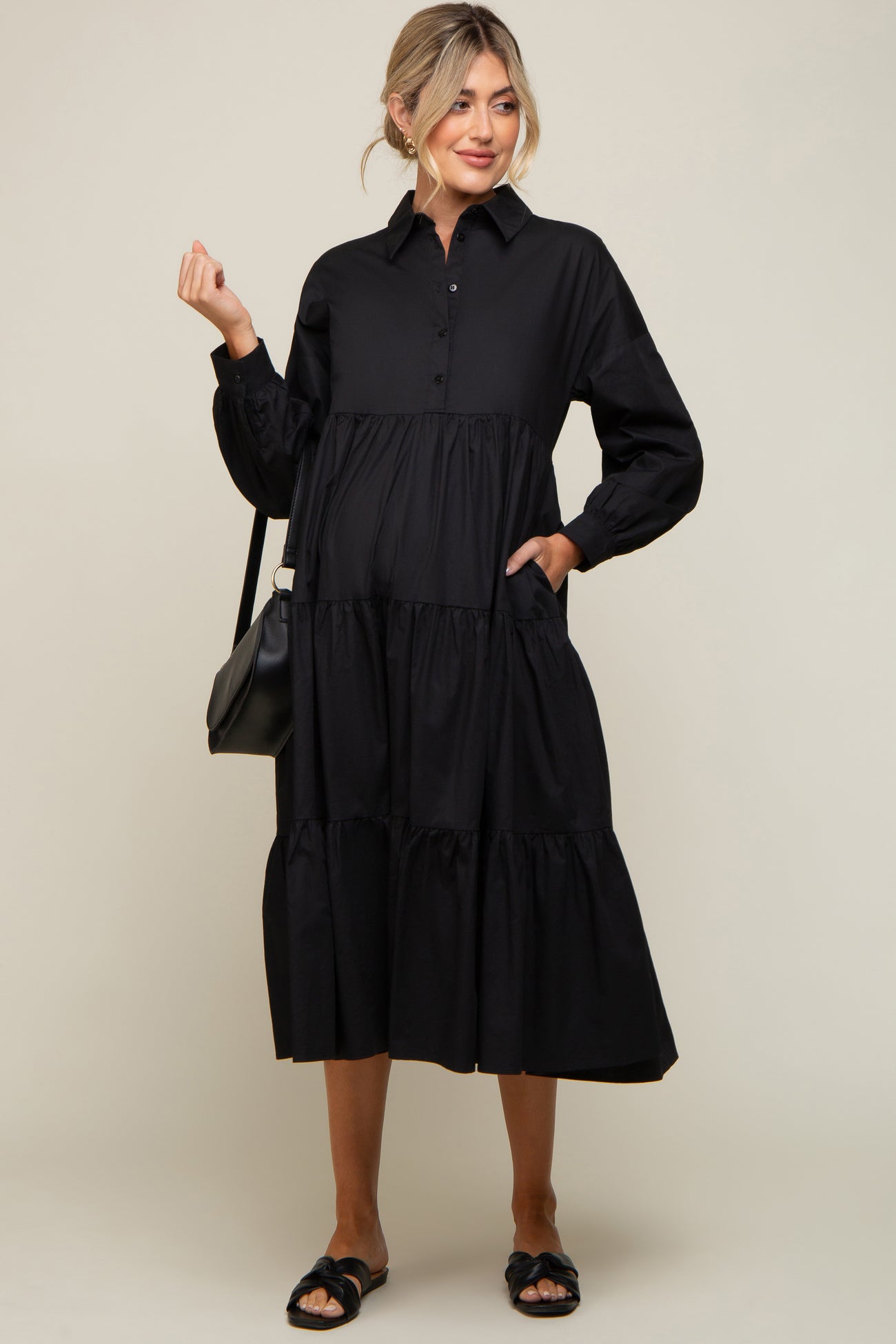 woman wearing a black long sleeve tiered maternity midi shirt dress with a black shoulder bag