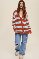 Woman wearing an oversized orange and blue striped fuzzy cardigan with distressed wide-leg jeans