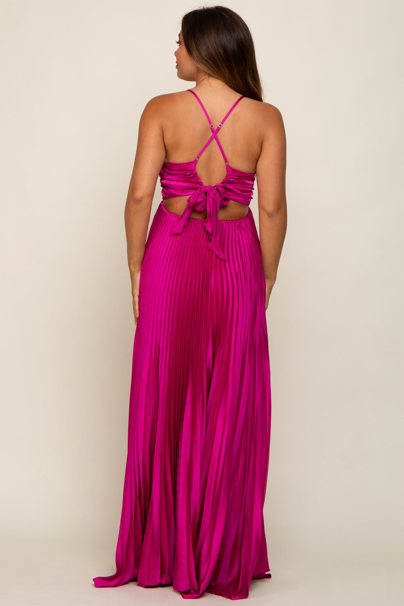 Back view of a woman wearing a magenta pleated maxi dress with a crisscross tie back