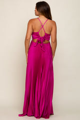 Back view of a woman wearing a magenta pleated maxi dress with a crisscross tie back