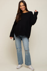 Woman wearing a black oversized knit sweater and distressed light wash jeans with white sneakers