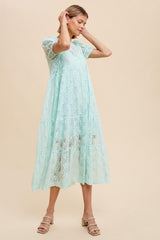 woman wearing a mint green lace midi dress with short sleeves and a tiered skirt