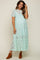 woman wearing a mint green lace maternity dress with short puff sleeves and a tiered skirt, showing her baby bump