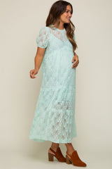 woman wearing a mint green lace maternity dress with puff sleeves and a tiered skirt, showcasing her baby bump