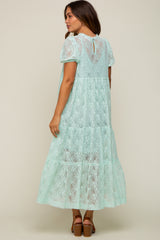 woman wearing a mint green lace maternity maxi dress with short sleeves and a tiered skirt
