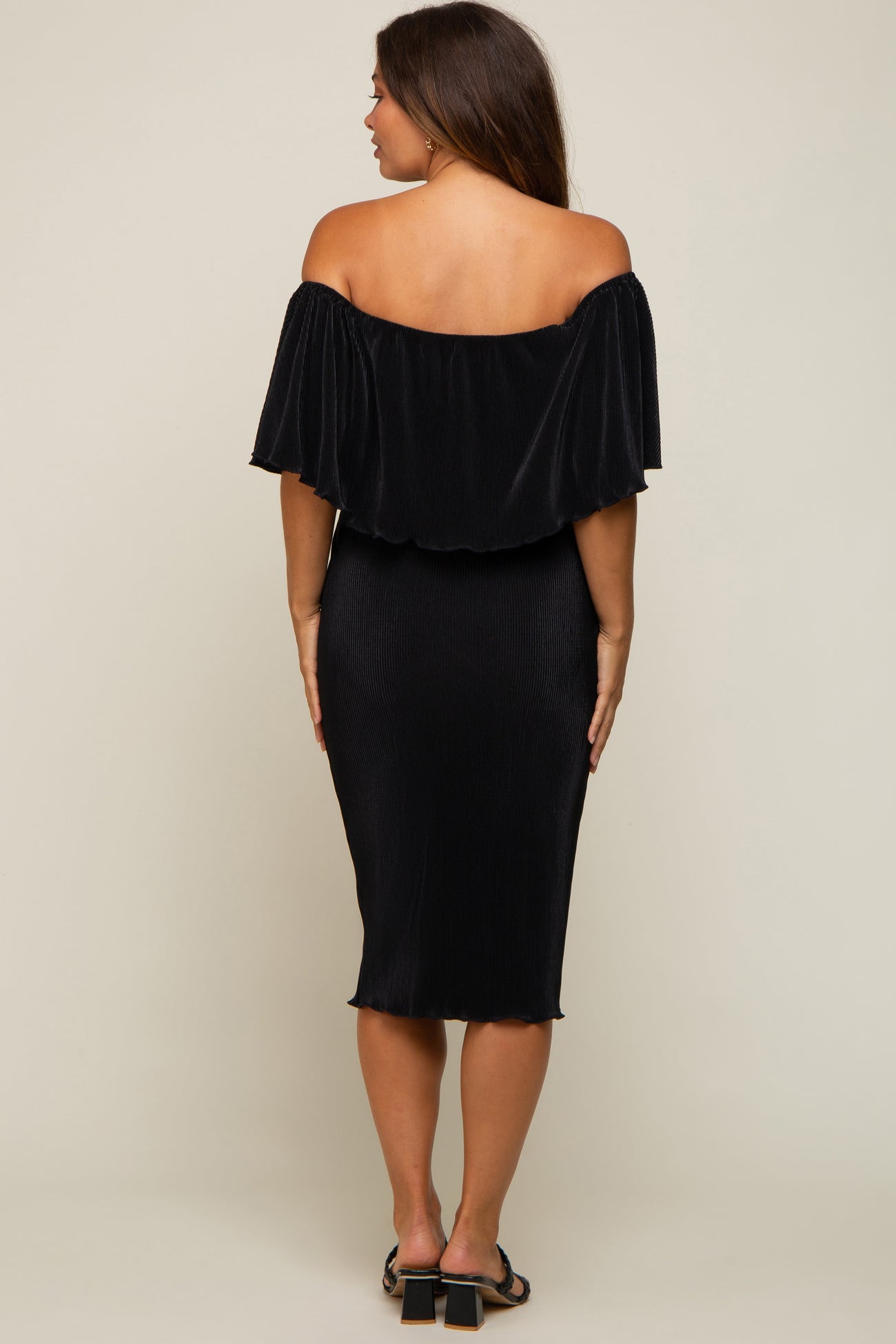 back view of woman wearing black off the shoulder pleated midi dress with ruffle overlay
