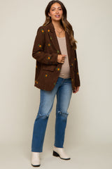 Pregnant woman wearing a brown floral embroidered corduroy blazer with distressed blue jeans and white boots