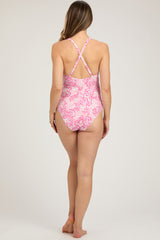 woman wearing a pink floral patterned maternity swimsuit with adjustable crisscross straps and a fitted design