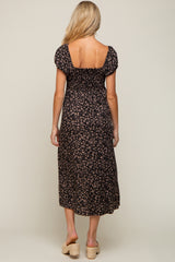 Back view of a woman wearing a black floral smocked midi dress with puff sleeves and tan wedge sandals
