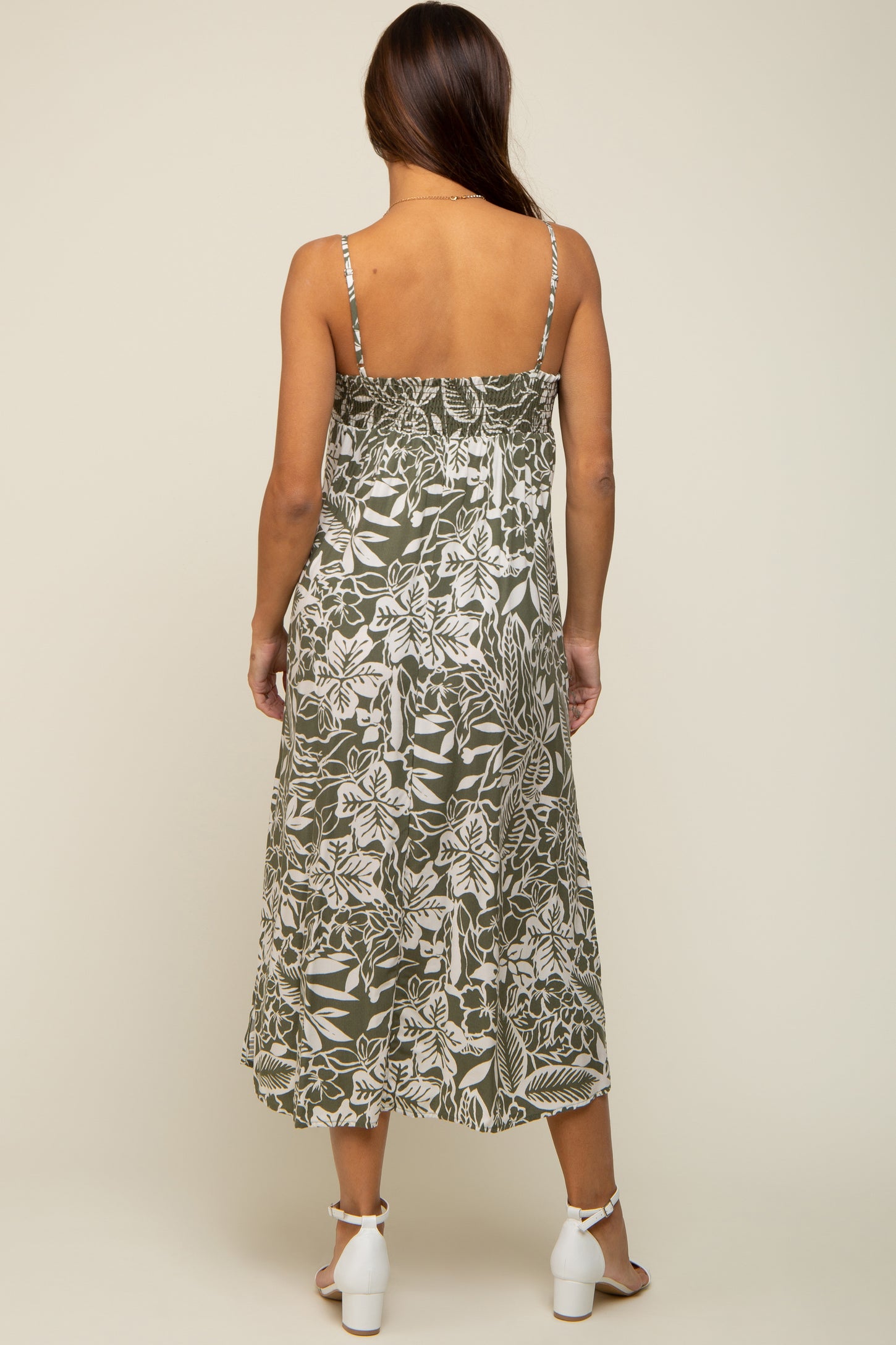 Back view of woman wearing olive green floral midi dress with smocked back and white block heel sandals
