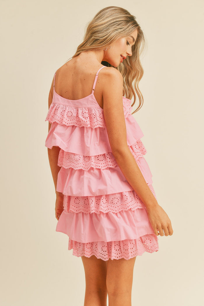 woman wearing a pink tiered ruffle dress with eyelet detailing and spaghetti straps