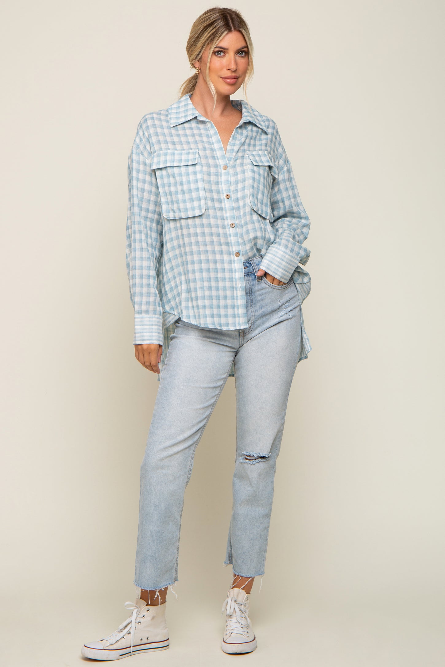 woman wearing light blue gingham button down shirt and distressed denim jeans with white sneakers